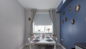 A dining area with a table set for four, a window with curtains, and decorative wall mirrors.