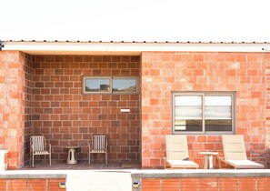 A brick building with two windows, a small table, and two chairs.