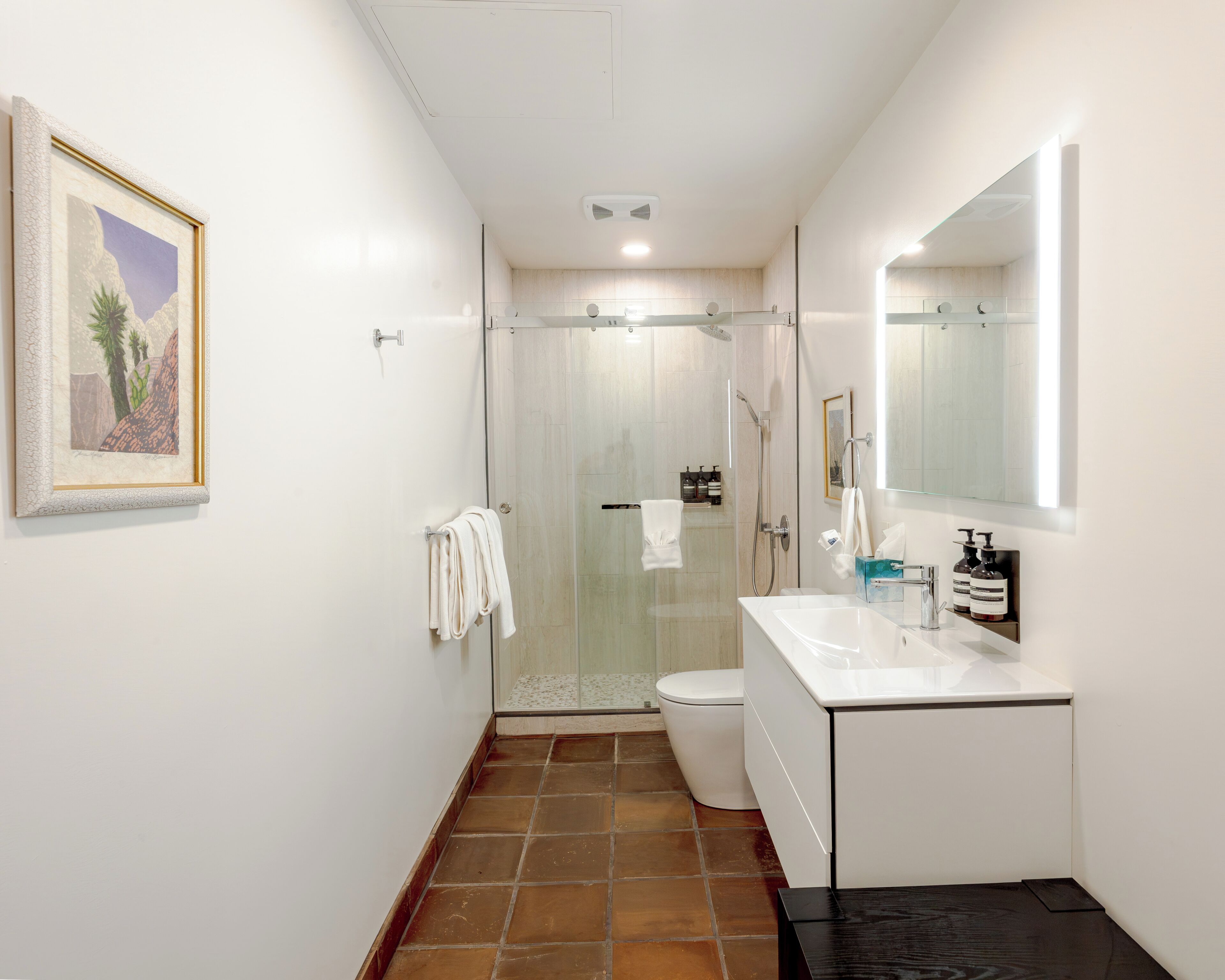 Un baño moderno con cabina de ducha de vidrio, un lavamanos blanco y un espejo grande.