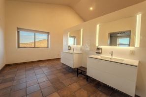 A bathroom with two sinks, a large mirror, and a window with a desert view.