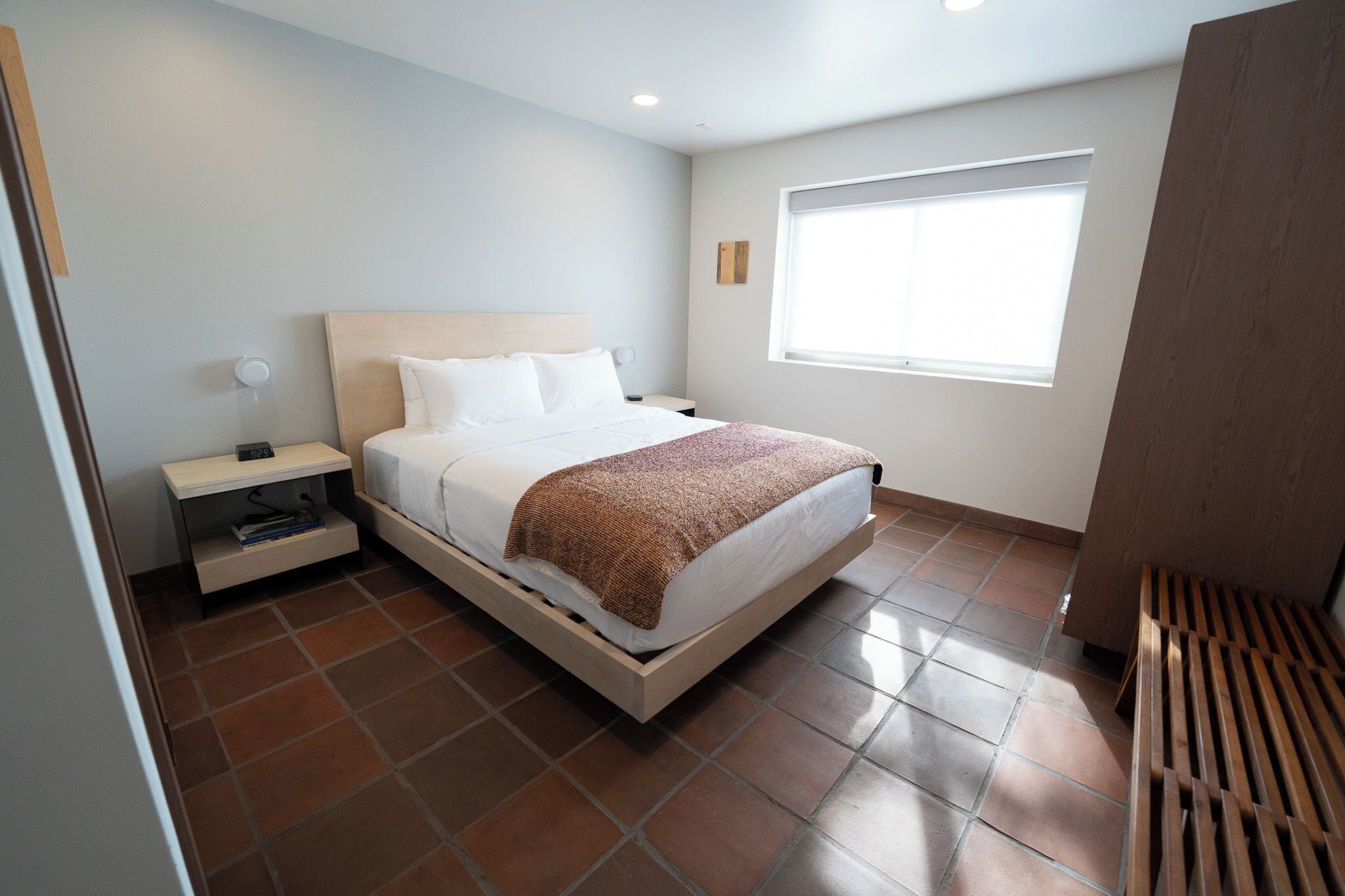 Un dormitorio moderno con cama, mesita de noche y ventana.