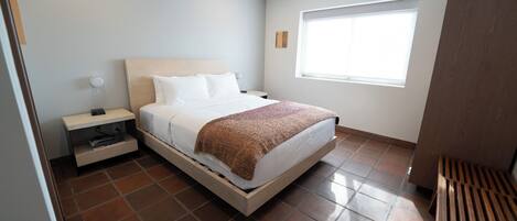 Un dormitorio moderno con cama, mesita de noche y ventana.