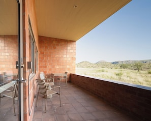 Une terrasse avec un mur en briques, une porte vitrée et une vue sur un paysage verdoyant.