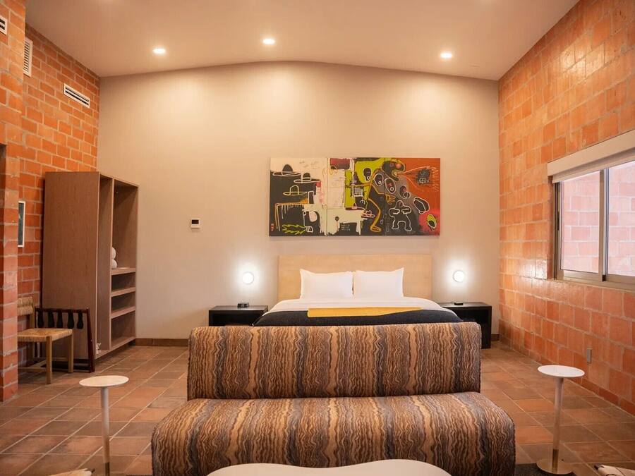 A bedroom with a bed, a nightstand, a chair, a small table, and a window.