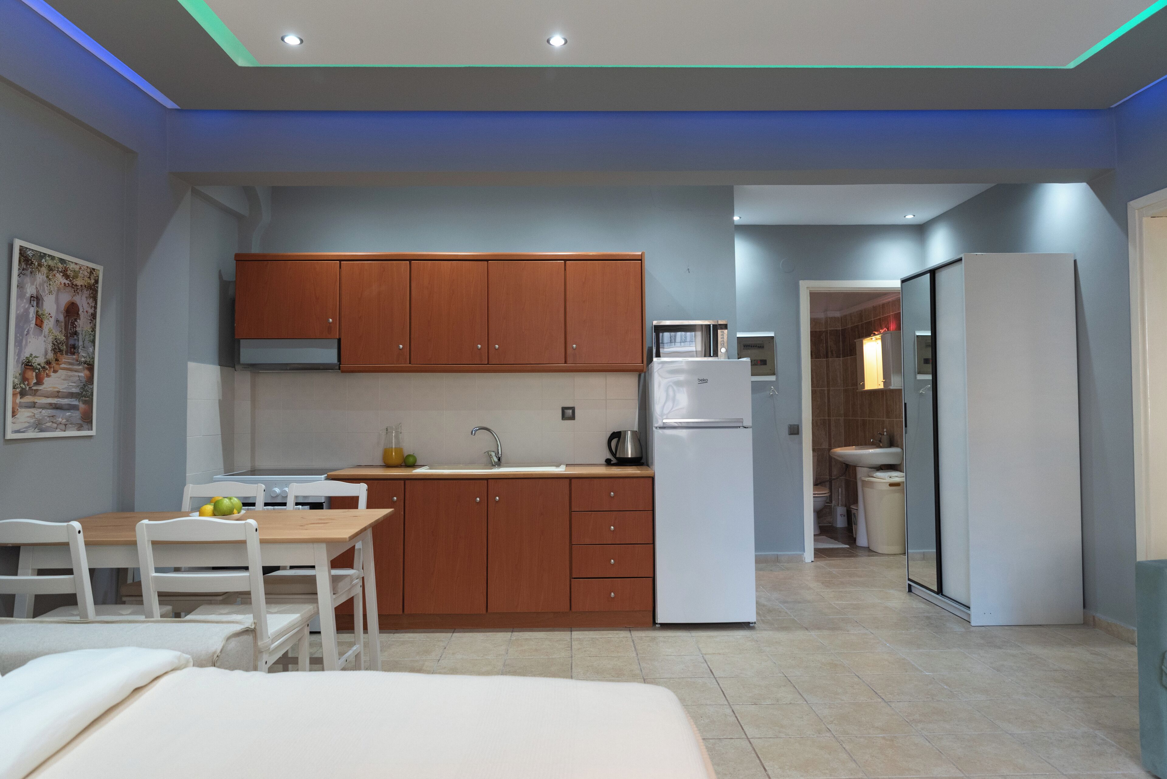 A modern kitchen with wooden cabinets, a white refrigerator, and a dining area with a table and chairs.