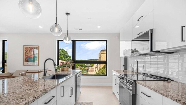 Una cocina moderna con una isla grande, electrodomésticos de acero inoxidable y vistas amplias a través de un ventanal.