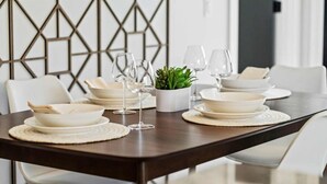 Una mesa de comedor dispuesta con platos, vasos y una pequeña planta en maceta.