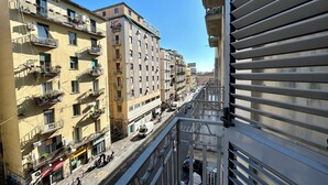 Un edificio de varios pisos con balcones, vista a la calle y un cielo azul despejado.