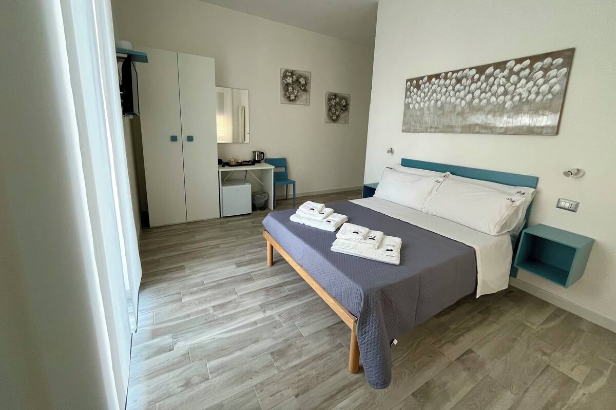A bedroom with a bed, a desk, and a chair.