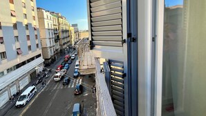Vista desde un balcón sobre una calle concurrida, edificios, cielo despejado y variedad de vehículos.