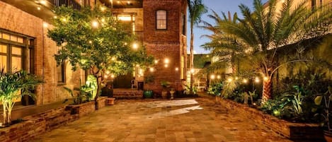 A courtyard with a pool, brick buildings, and string lights.