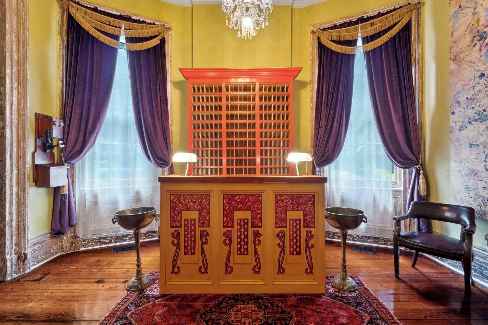 A room with a wooden altar, purple curtains, a chandelier, and a patterned rug.
