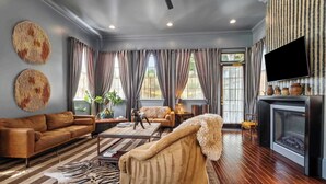 A modern living room with a sofa, armchair, and a fireplace. - Elegant Tribal House w heated Pool/Hot Tub (New Orleans)