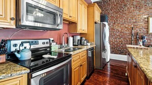 Una cocina con armarios de madera, un microondas de acero inoxidable, una estufa y un refrigerador.