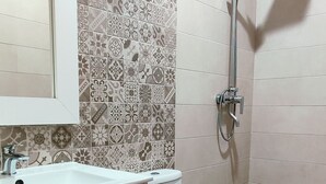 Een badkamer met een wit wastafelmeubel, toilet en douche.