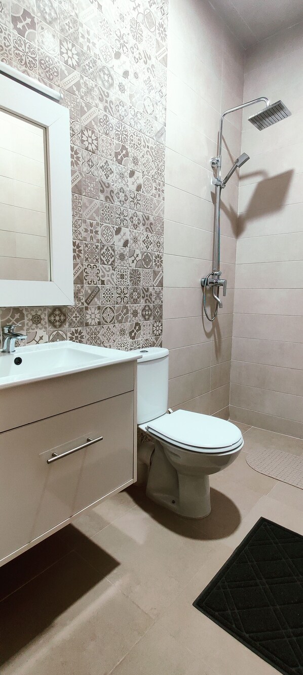 A bathroom with a white sink, a toilet, and a shower.