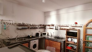 Een praktische keuken met een ingebouwde wasmachine, een magnetron en een spoelbak.