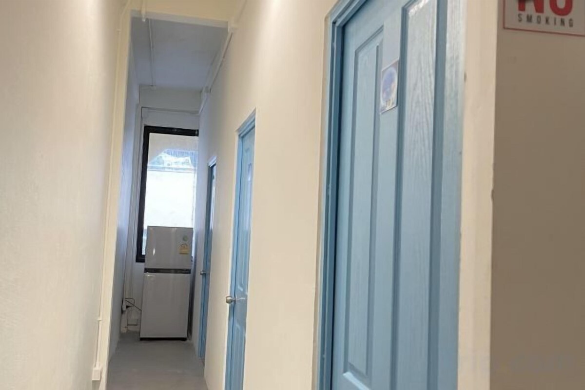 Un pasillo estrecho con un refrigerador y una puerta con letrero de 'No Fumar'.