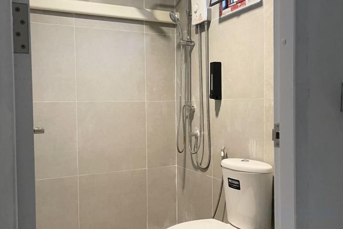 Un baño con ducha, inodoro y panel de control en la pared.