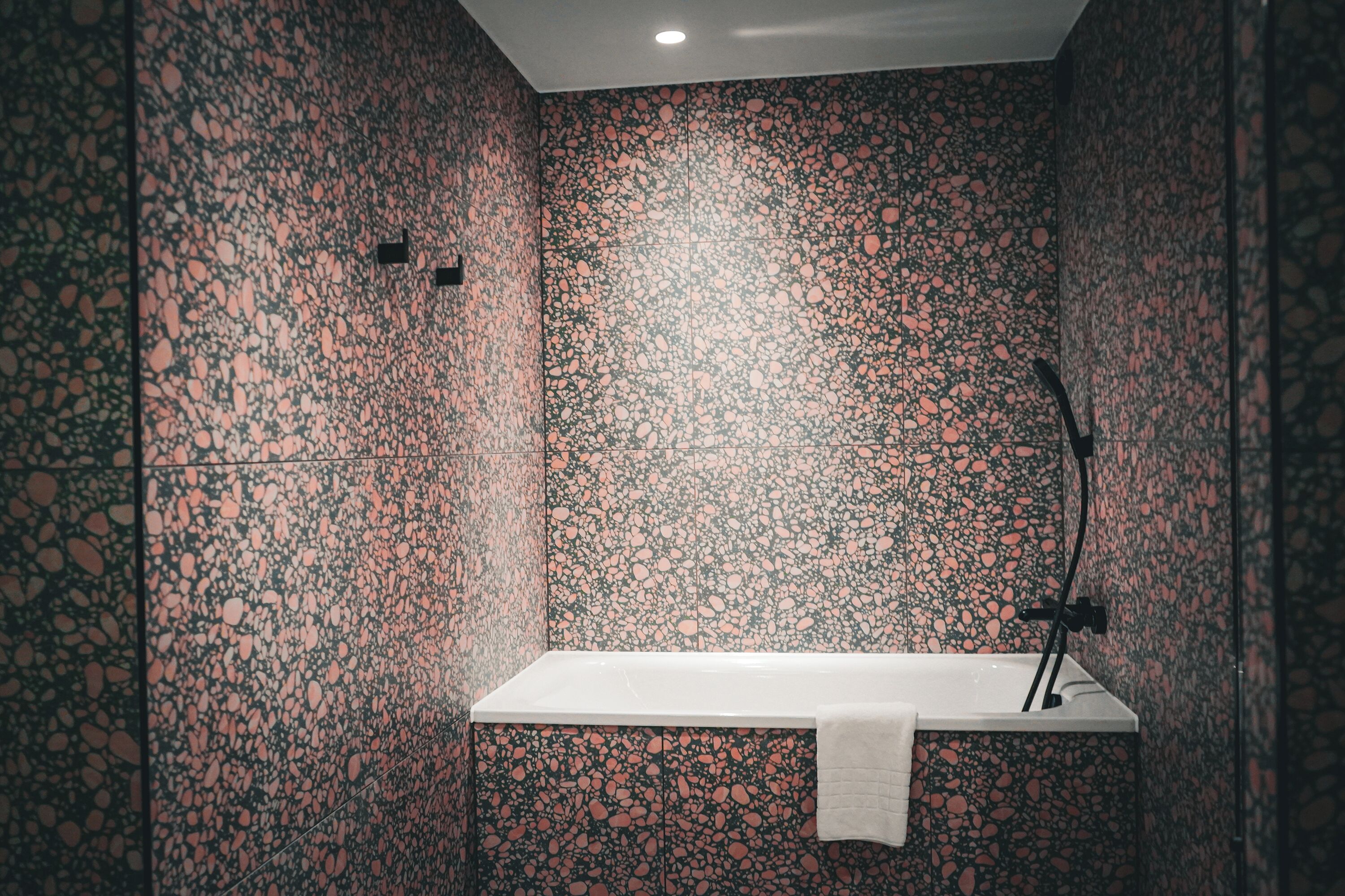 A modern bathroom with a terrazzo floor, a white sink, and a towel hanging on the wall.
