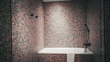 Ein modernes Badezimmer mit Terrazzo-Boden, einem weißen Waschbecken und einem Handtuch an der Wand.