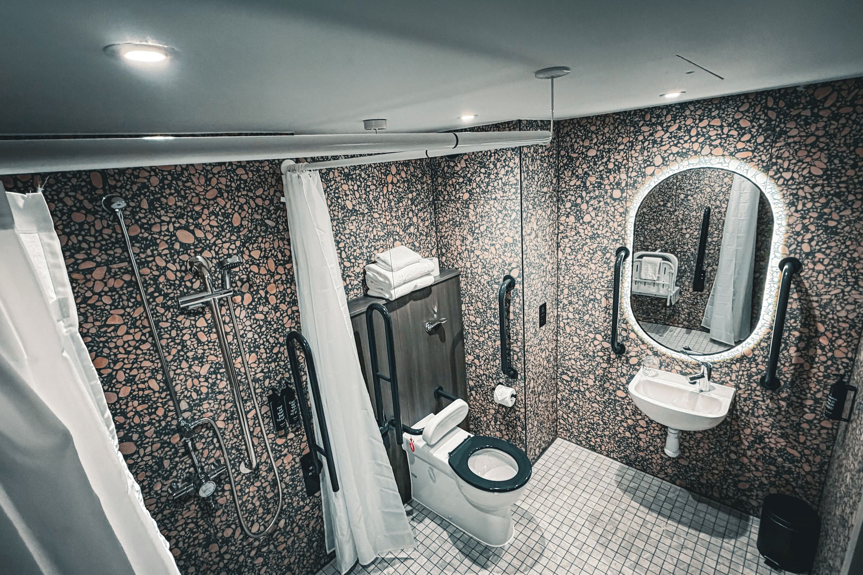 A modern bathroom with a black toilet, white sink, and a shower area.