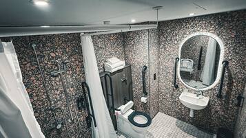 Un baño moderno con inodoro negro, lavamanos blanco y zona de ducha.