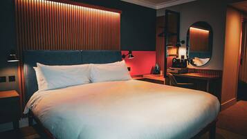 Une chambre d’hôtel avec un grand lit, des tables de chevet, un bureau et un miroir.