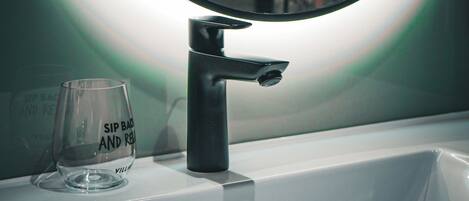 A bathroom sink with a clear glass and a mirror.