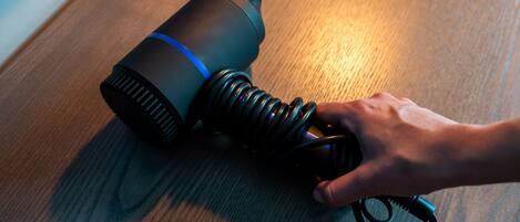 A hand adjusting a black coiled cable on a wooden surface.