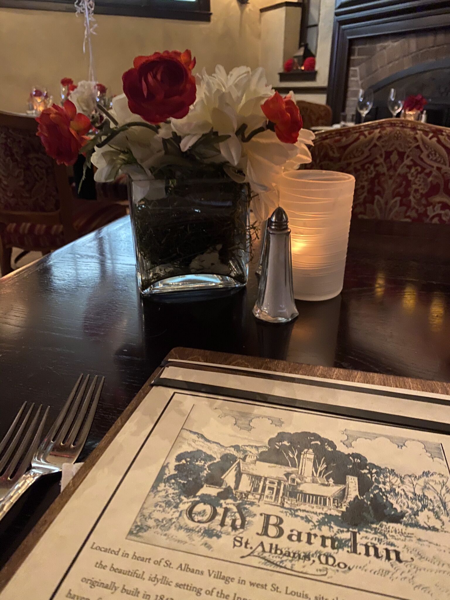 Una mesa con un menú, un salero y un florero con flores.