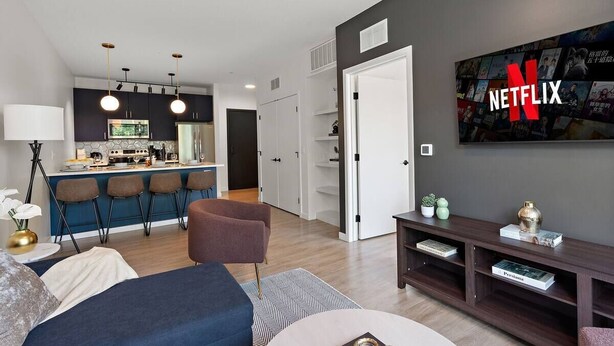Un salon moderne avec un canapé, une table basse et un mur dédié à la télévision, orné du logo Netflix.