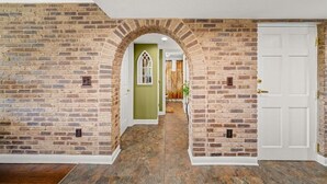 A hallway with brick walls, a white door, and a green door at the end. - Penthouse Paradise | Smoky Mtn Views & Jacuzzi (Pigeon Forge)