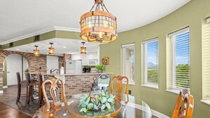 A dining area with a glass table, wooden chairs, a brick backsplash, and a hanging light fixture. - Penthouse Paradise | Smoky Mtn Views & Jacuzzi (Pigeon Forge)