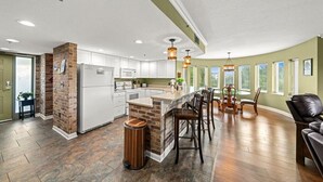 A spacious kitchen with a central island, white cabinetry, and a brick accent wall. - Penthouse Paradise | Smoky Mtn Views & Jacuzzi (Pigeon Forge)