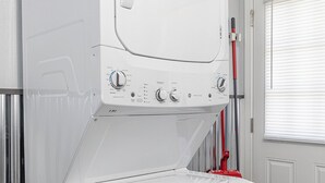 Una rentadora i una assecadora apilades en una habitació amb una porta i una finestra.