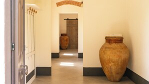 A hallway with a large vase, a wooden door, and a wall-mounted towel rack.