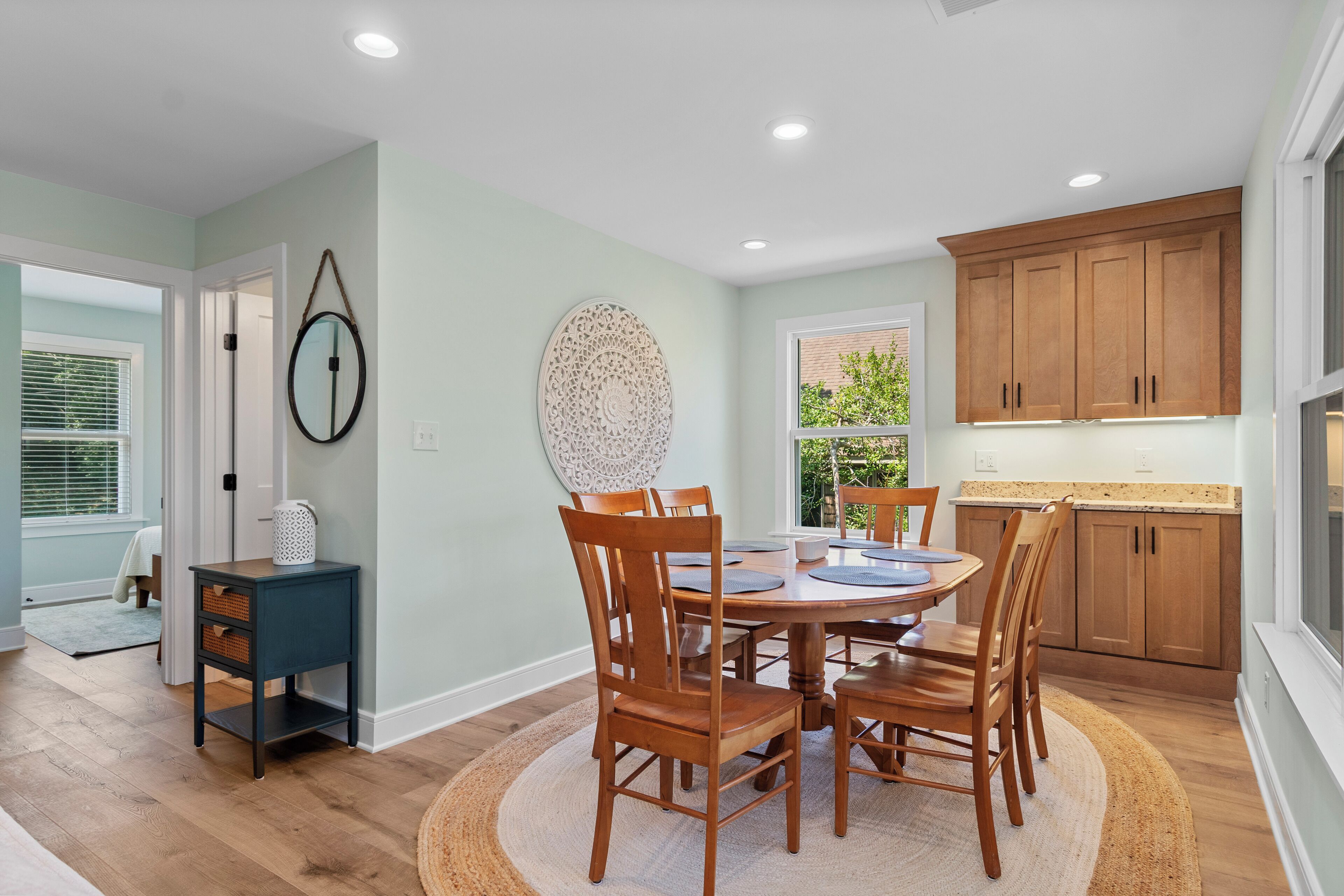 A dining area with a round table, wooden chairs, and a small side table with baskets.