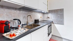 A modern kitchen with a black countertop, stainless steel sink, and a red appliance.