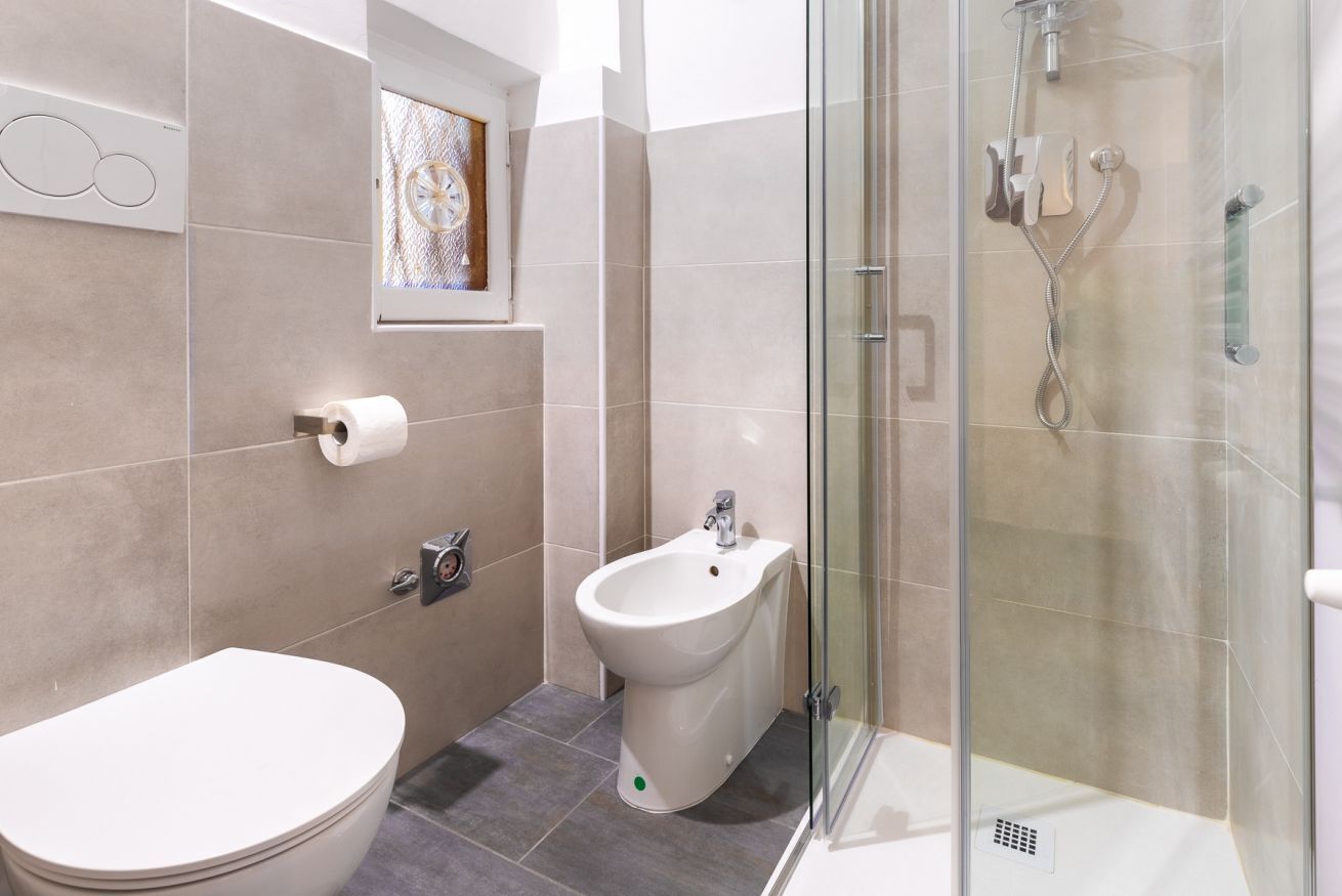 A bathroom with a toilet, bidet, and glass-enclosed shower.