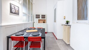 A dining area with a table set for four, red chairs, a white cabinet, and a radiator.