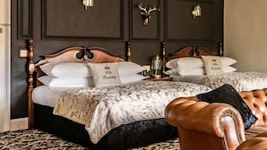A bedroom with a double bed, two nightstands, a chandelier, and a decorative wall panel. - Caer Beris Hotel (Builth Wells)