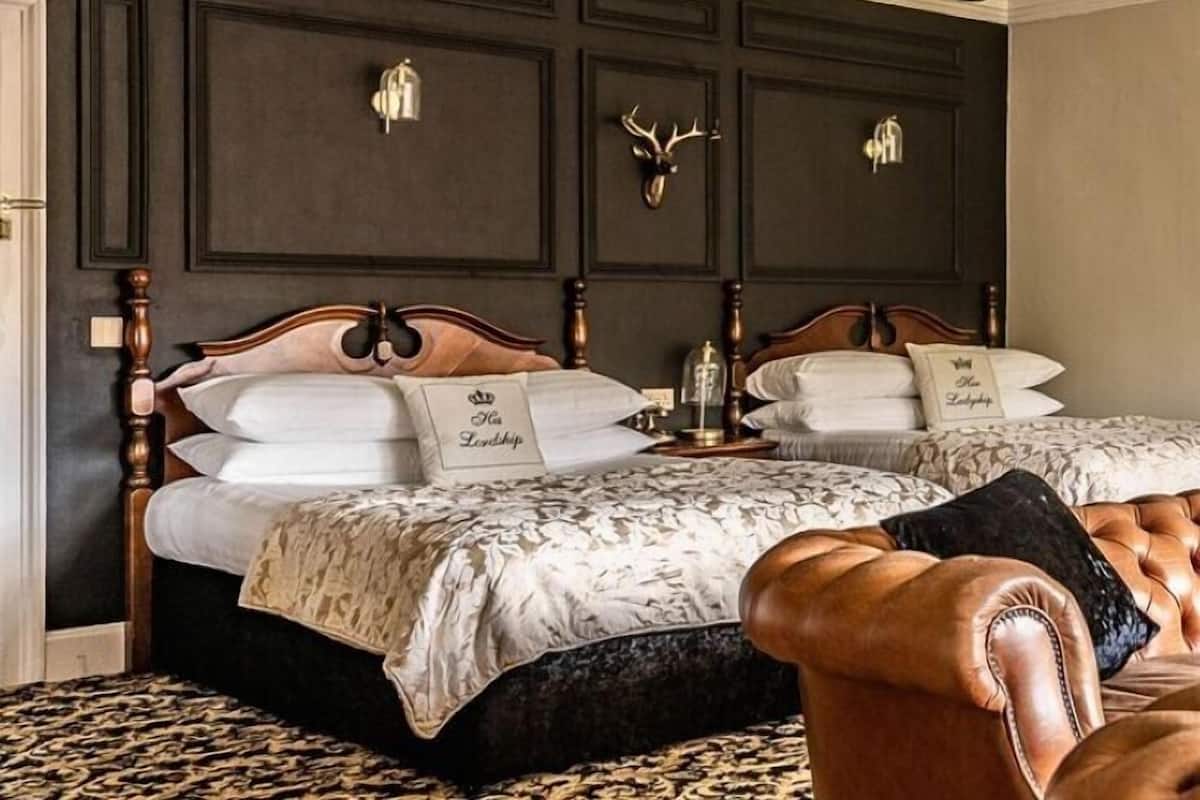 A bedroom with a double bed, two nightstands, a chandelier, and a decorative wall panel.