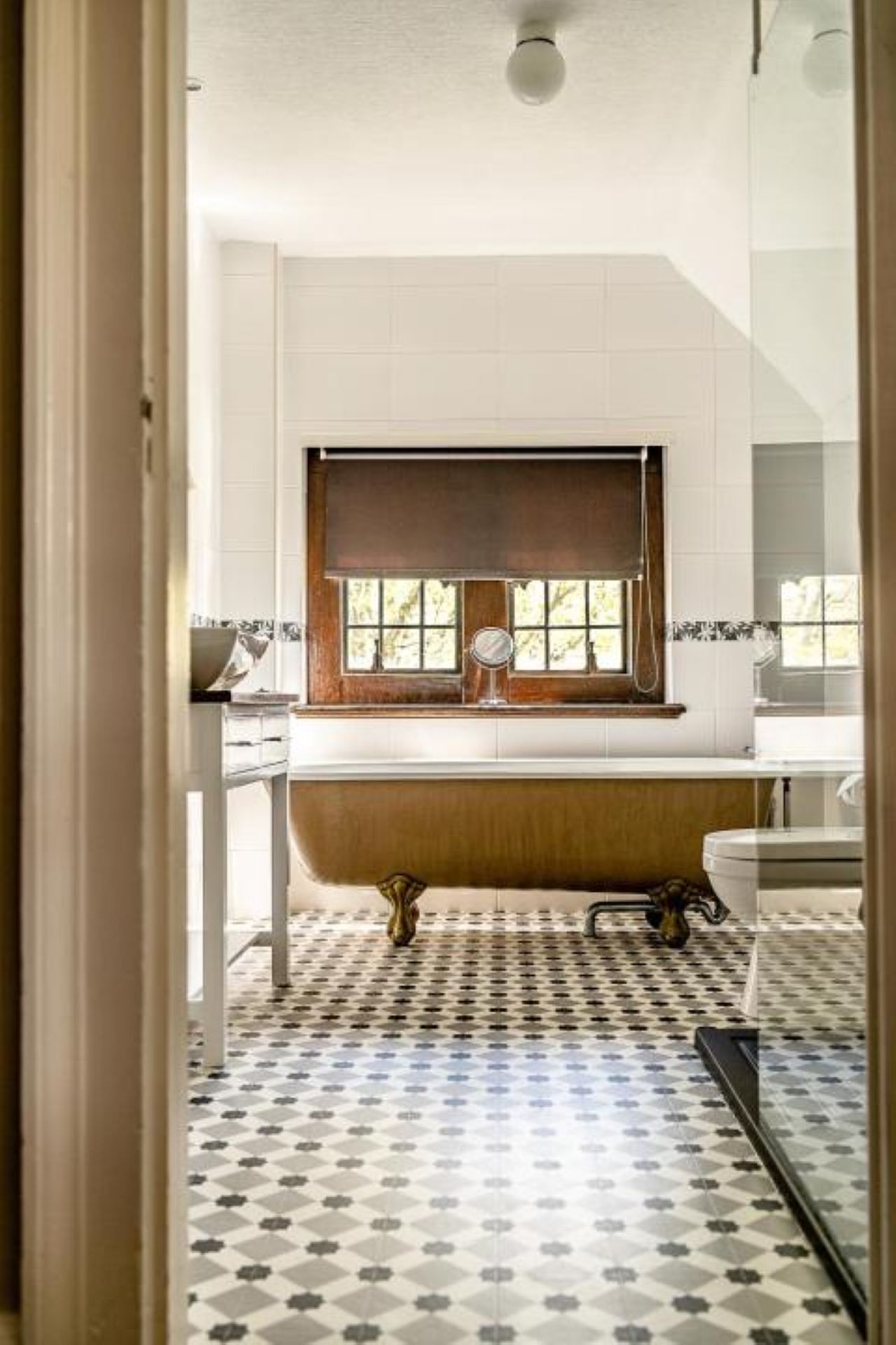 Un baño con bañera, ventana y piso estampado.
