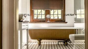 Un baño con bañera, ventana y piso estampado.