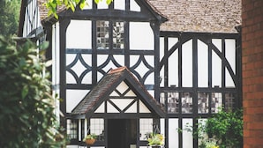 A Tudor-style building with a symmetrical facade, a steeply pitched roof, and a gravel driveway. - Caer Beris Hotel (Builth Wells)