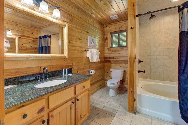 A wooden cabin bathroom with a sink, toilet, and bathtub.