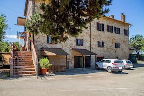 A stone building with a staircase, two doors, and a parked white car.