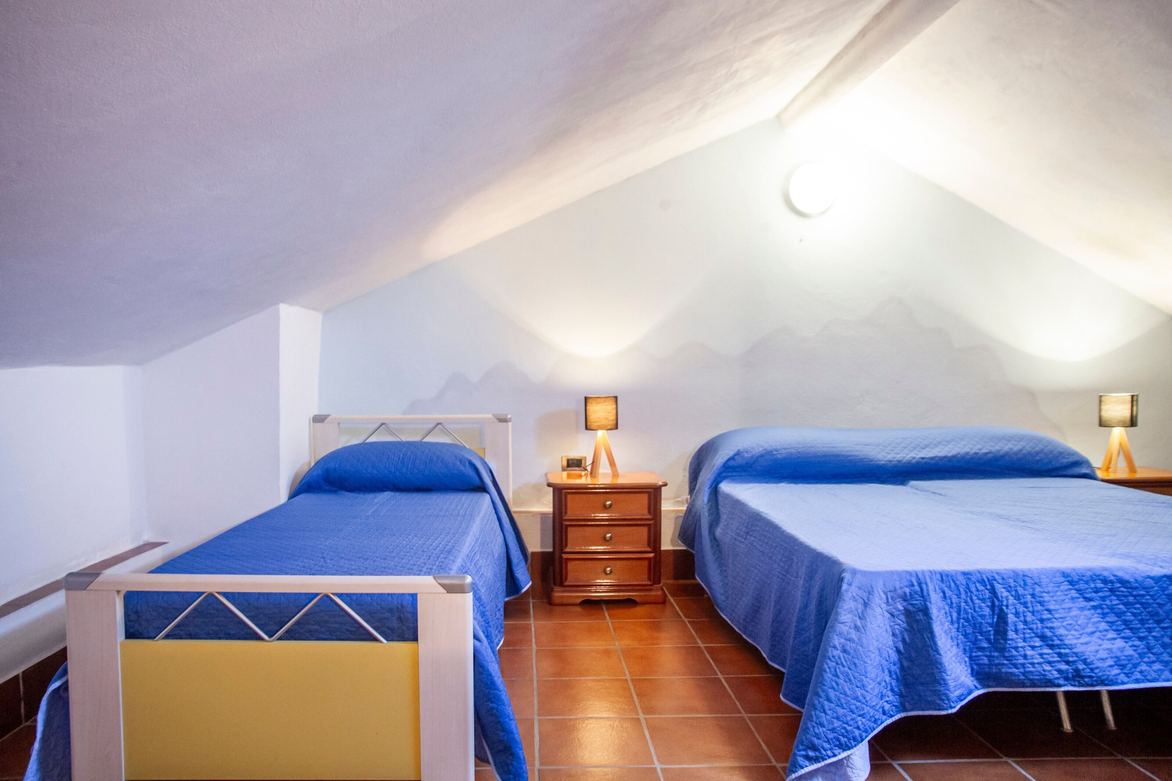 Een slaapkamer met twee bedden, een nachtkastje met een lamp en een raam met uitzicht op bergen.