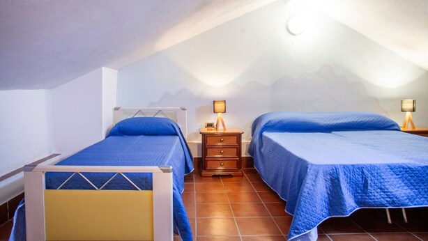 Un dormitorio con dos camas, una mesita de noche con lámpara y una ventana con vistas a las montañas.